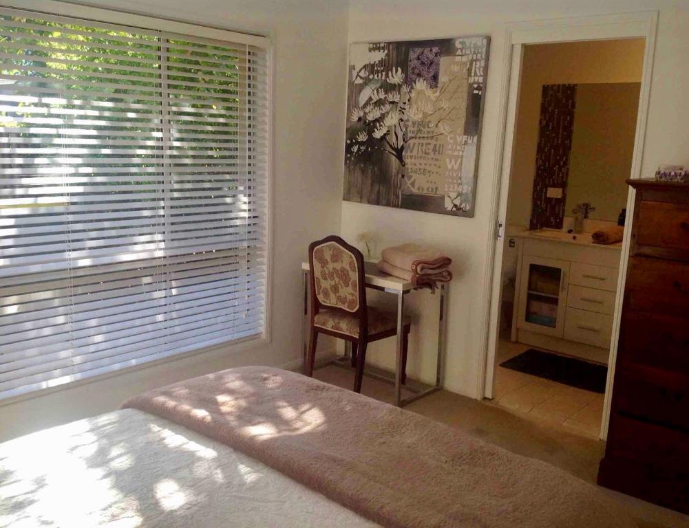 a bedroom with a bed and a desk and a window at Brisbane Bayside Retreat in Birkdale