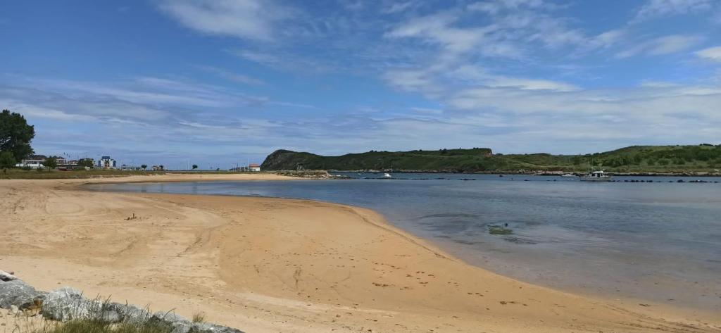 a beach with sand and water on a cloudy day at Apartamento Sol deluxe Suances in Suances