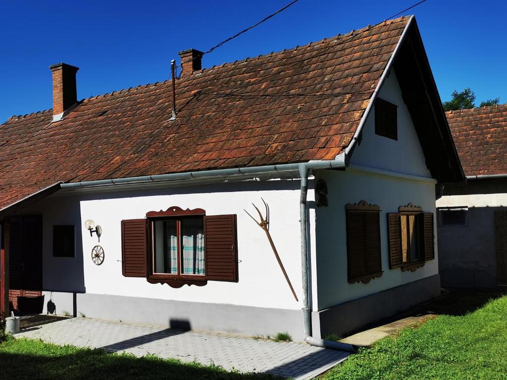 una pequeña casa blanca con techo marrón en Őrség Kincse en Hegyhátszentjakab