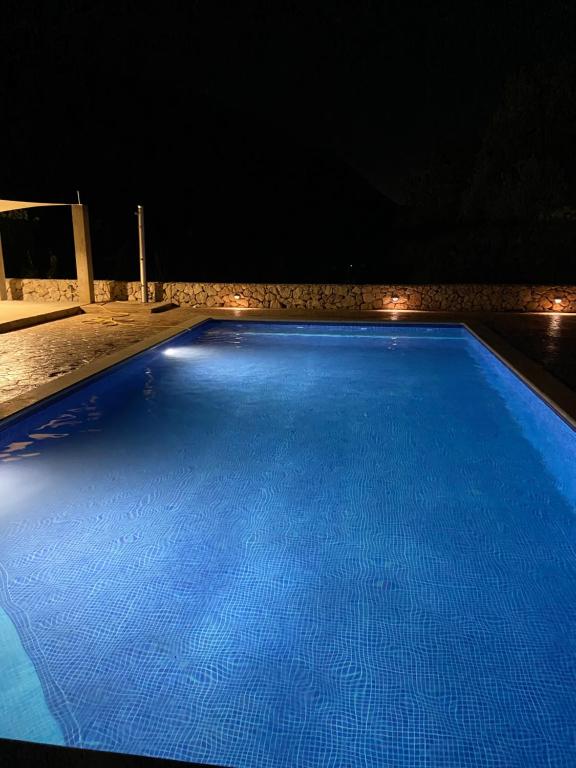 a large blue swimming pool at night with lights at Mate in Zagvozd