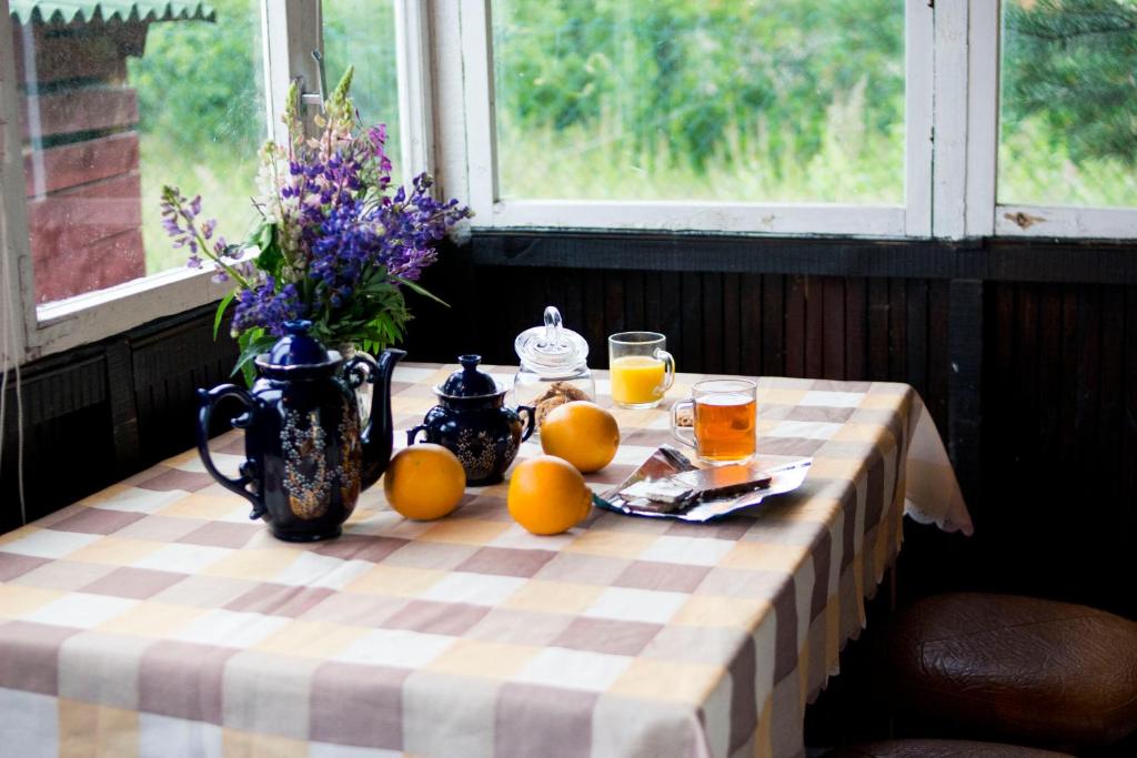 a table with oranges and a vase of flowers and juice at Summer mini cottage in Tsentral'nyy Poselok