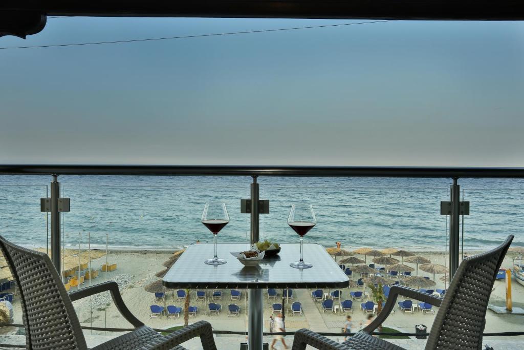 a table with two glasses of wine on the beach at Hotel Dionisos in Leptokarya