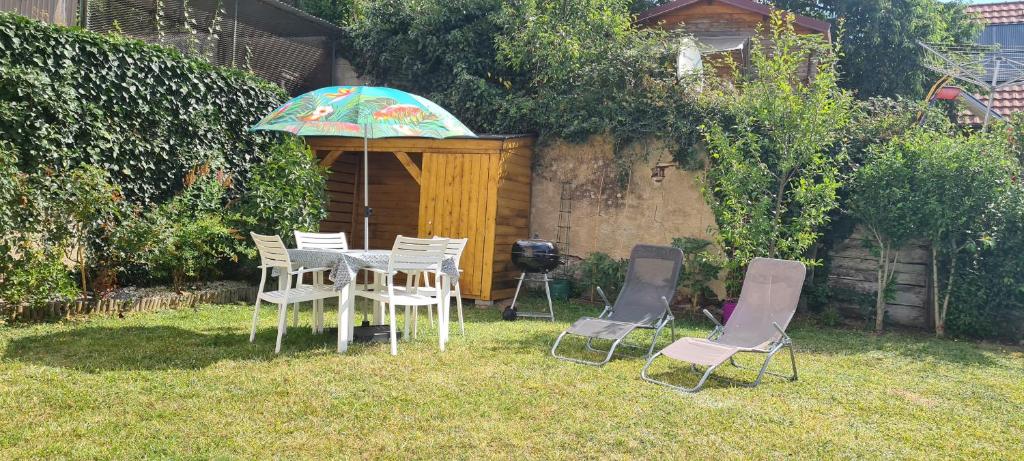 a table and chairs with an umbrella in a yard at L orée du Saint-Gangolphe in Lautenbach