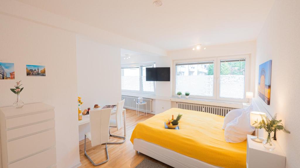 a white bedroom with a yellow bed and a desk at Relax Aachener Boardinghouse Appartements Premium 1 in Aachen