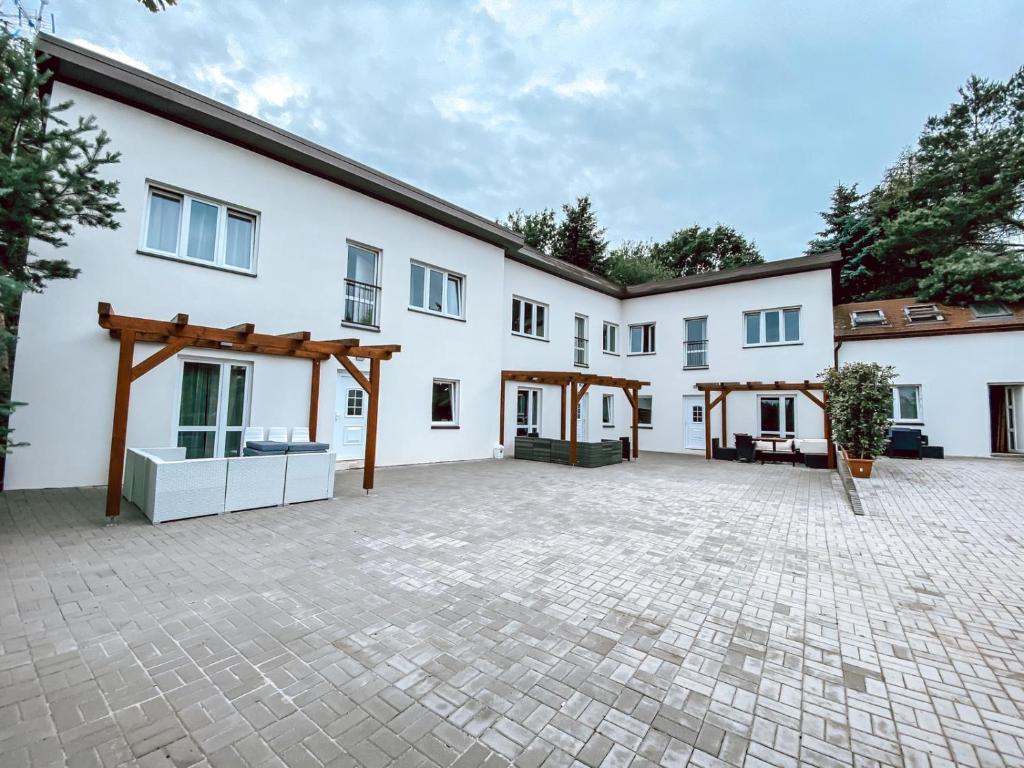 an exterior view of a white building with a courtyard at Chaty a Apartmány Hracholusky Kemp Kosatka in Pňovany