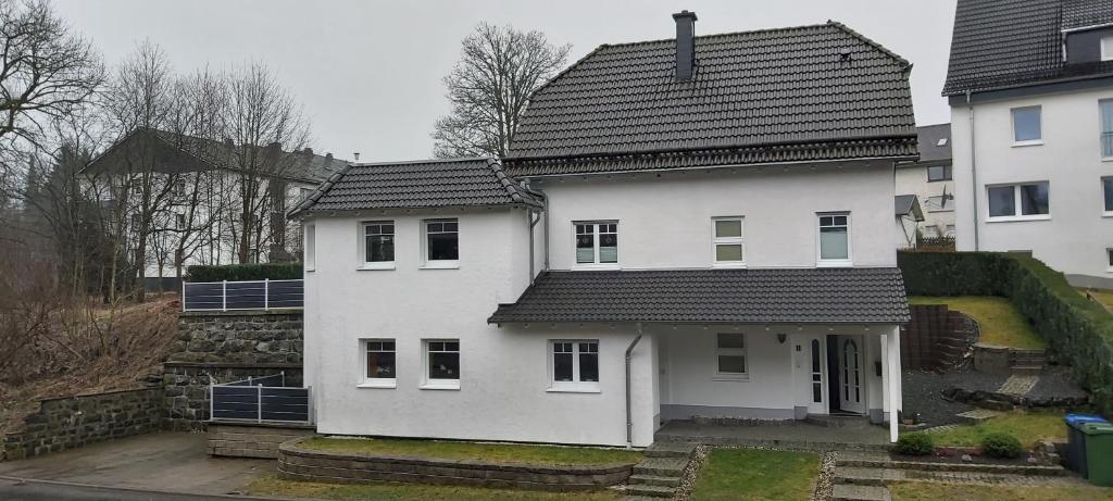 uma casa branca com um telhado preto em Ferienwohnung Gashi em Winterberg