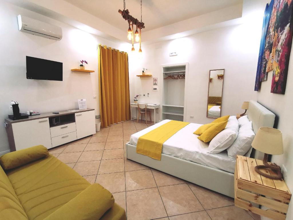 a bedroom with a bed and a tv and a couch at I Tesori di Napoli in Naples