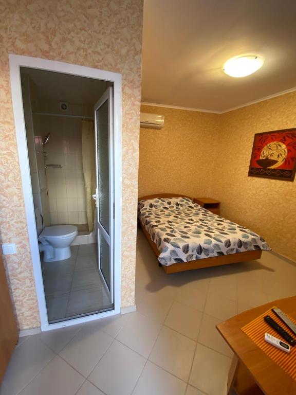 a bathroom with a bed and a toilet in a room at Гостевой дом Домашний на Черноморской in Vityazevo