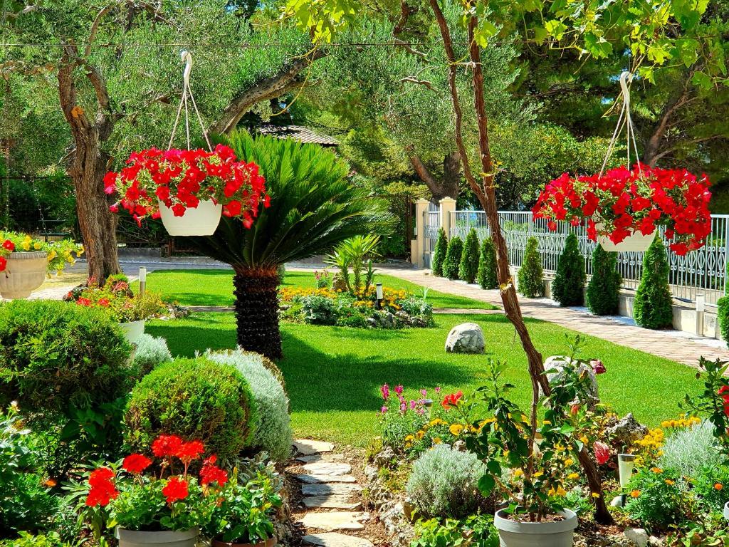 un jardín con flores rojas en macetas colgantes en Guest House Antonia, en Baška Voda