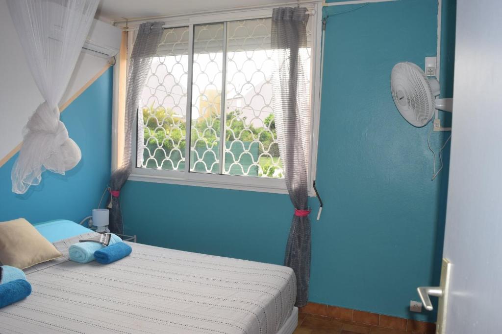 a blue bedroom with a bed and a window at Le Paradis des Doudous/Résidence Corail in Sainte-Anne