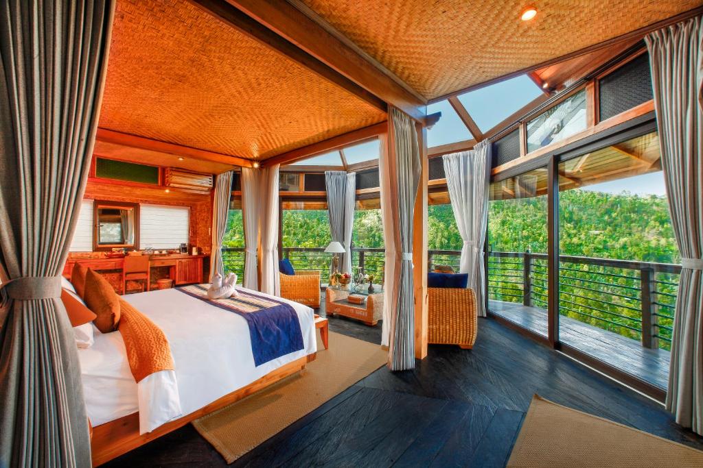 a bedroom with a bed in a room with windows at Munduk Heaven Luxury Villas in Munduk