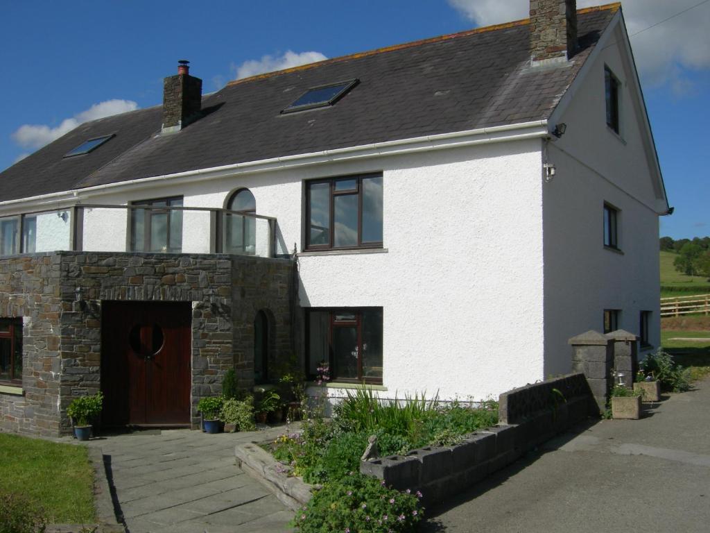 biały ceglany dom z brązowymi drzwiami w obiekcie Alltyfyrddin Farm Guest House at The Merlin's Hill Centre w mieście Carmarthen