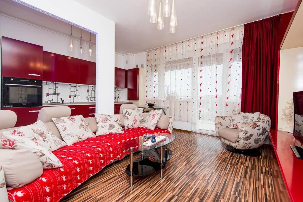 a living room with a red couch and two chairs at Relaxing Spa Apartment in Arad