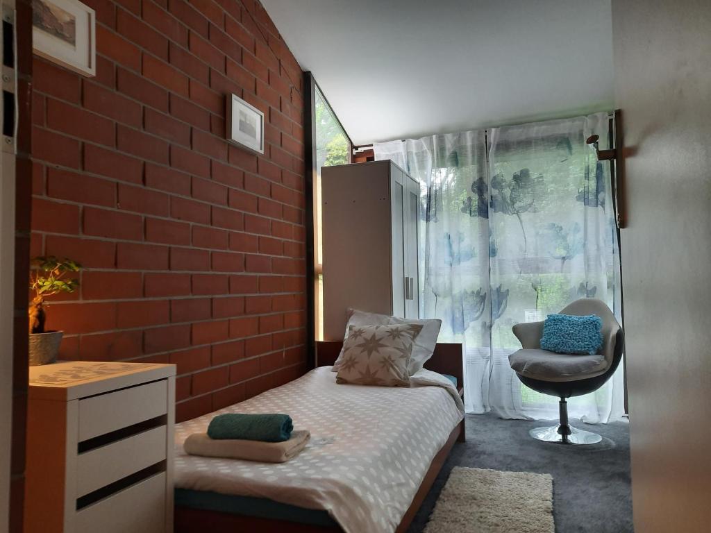 1 dormitorio con pared de ladrillo, cama y silla en Ochota Forest Guest House, en Varsovia