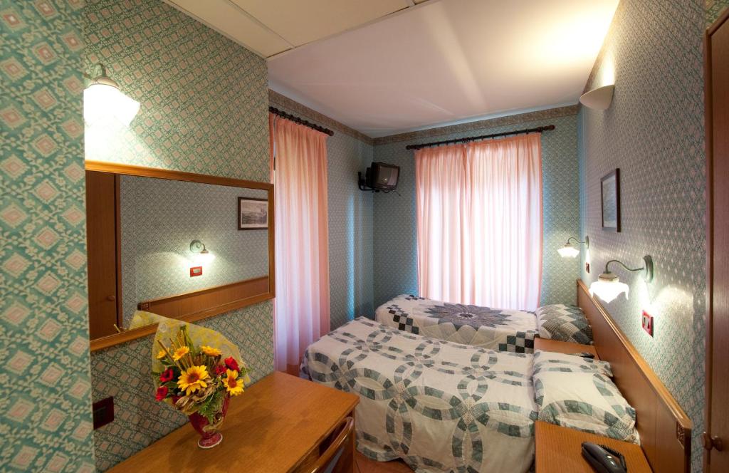 a hotel room with two beds and a mirror at Hotel Palavas in Villar Pellice