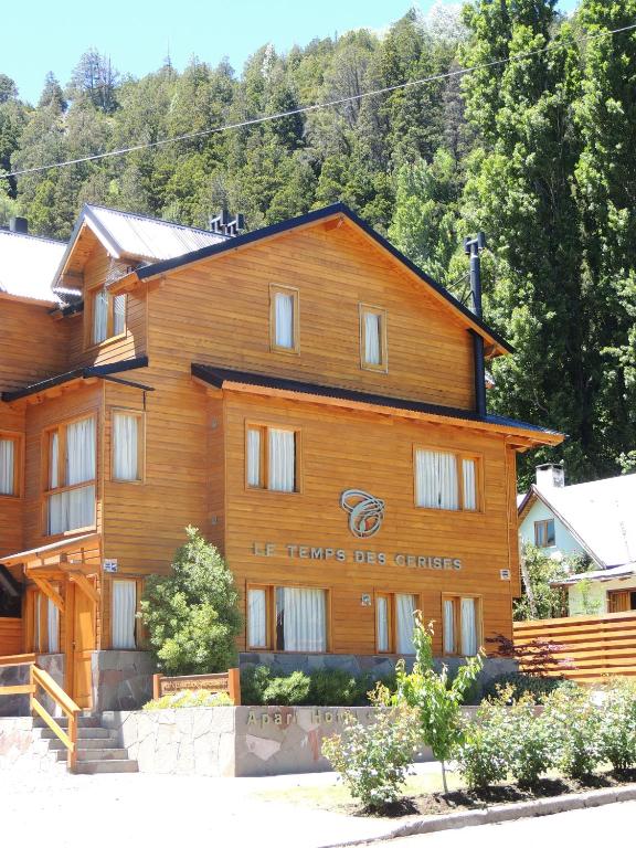 a large wooden building with a sign on it at Apart Hotel Le Temps Des Cerises in San Martín de los Andes