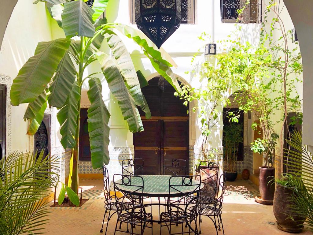 マラケシュにあるリヤド アル マモウネの植物のある中庭にテーブルと椅子