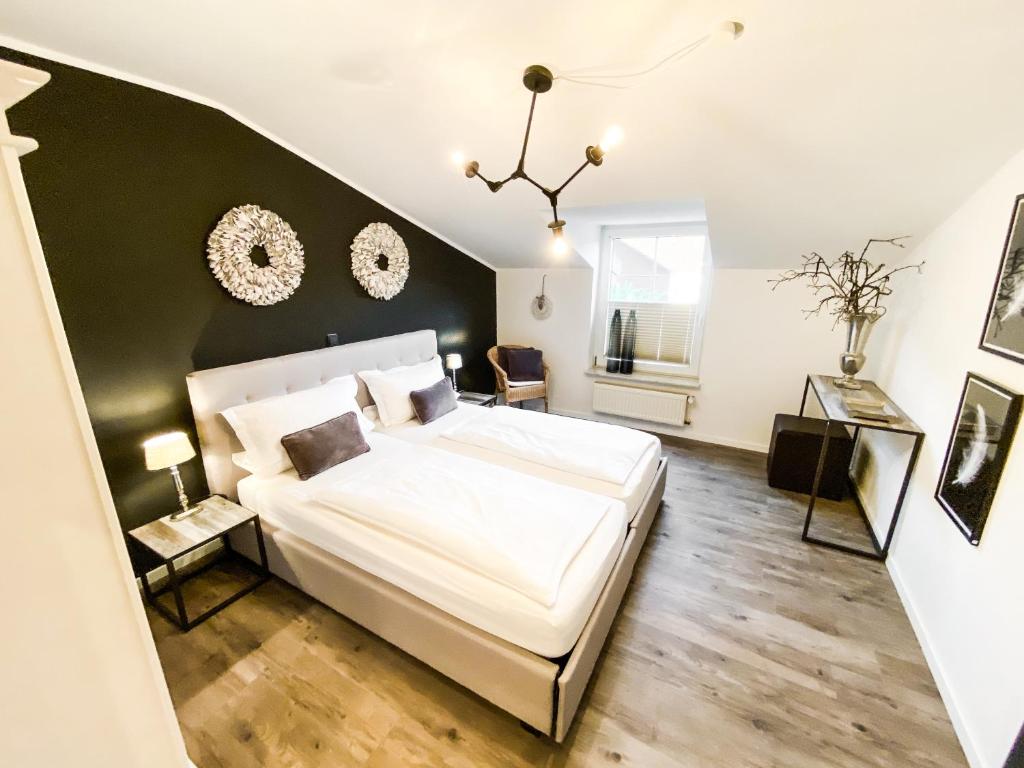 ein Schlafzimmer mit einem großen weißen Bett und einer schwarzen Wand in der Unterkunft Boutique Apartment Anne in Bad Harzburg