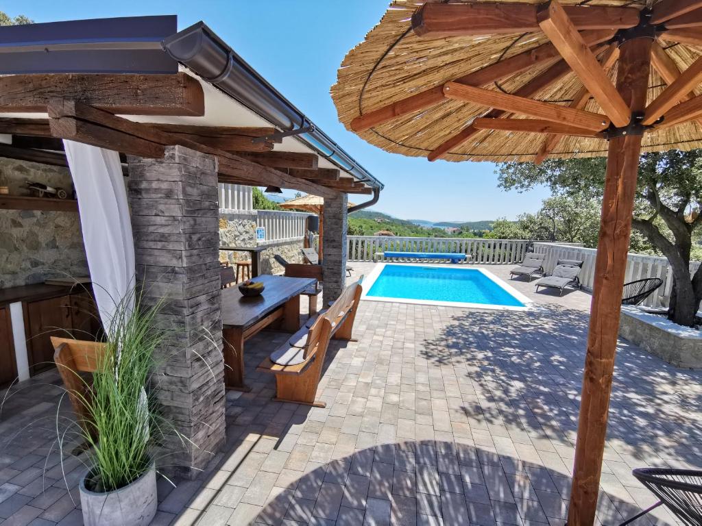 a patio with a wooden umbrella and a pool at Vila Marija in Rab