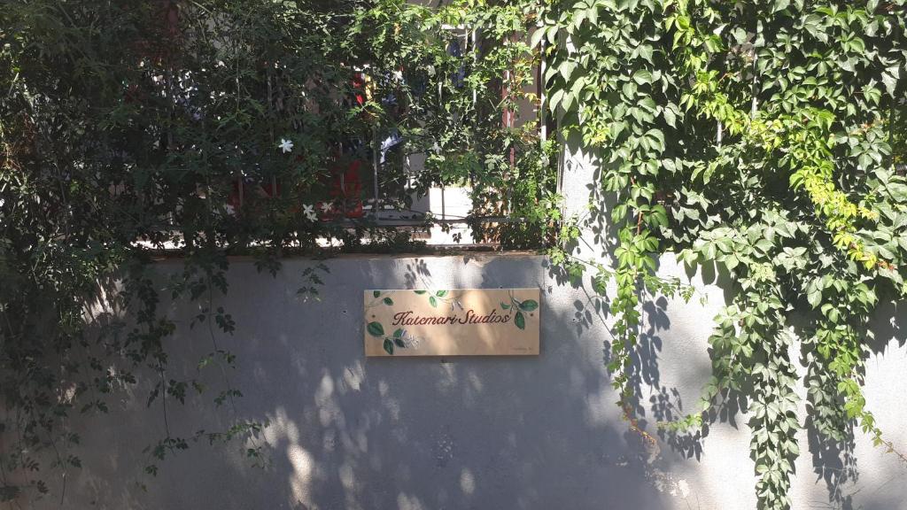 a sign on the side of a wall with trees at Kate-Mari studios in Skala
