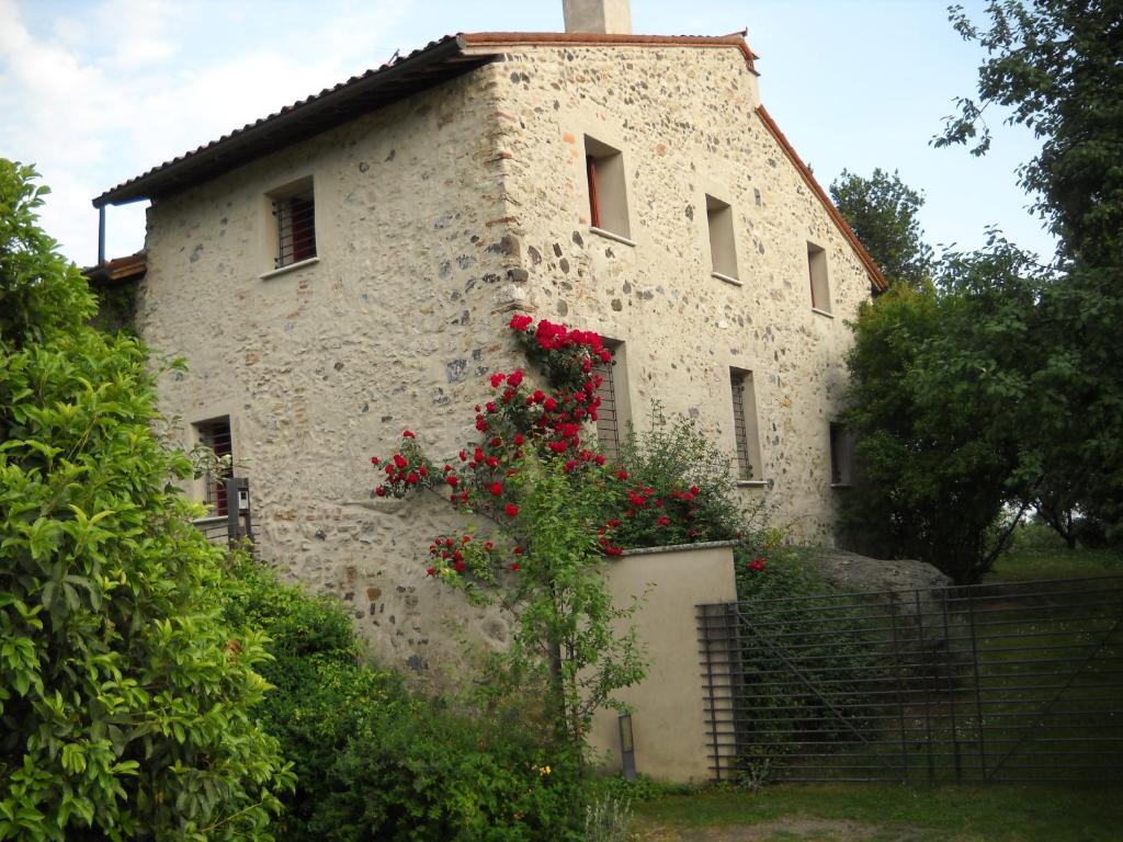 un viejo edificio de piedra con flores rojas. en Al Cantico, en Mason Vicento