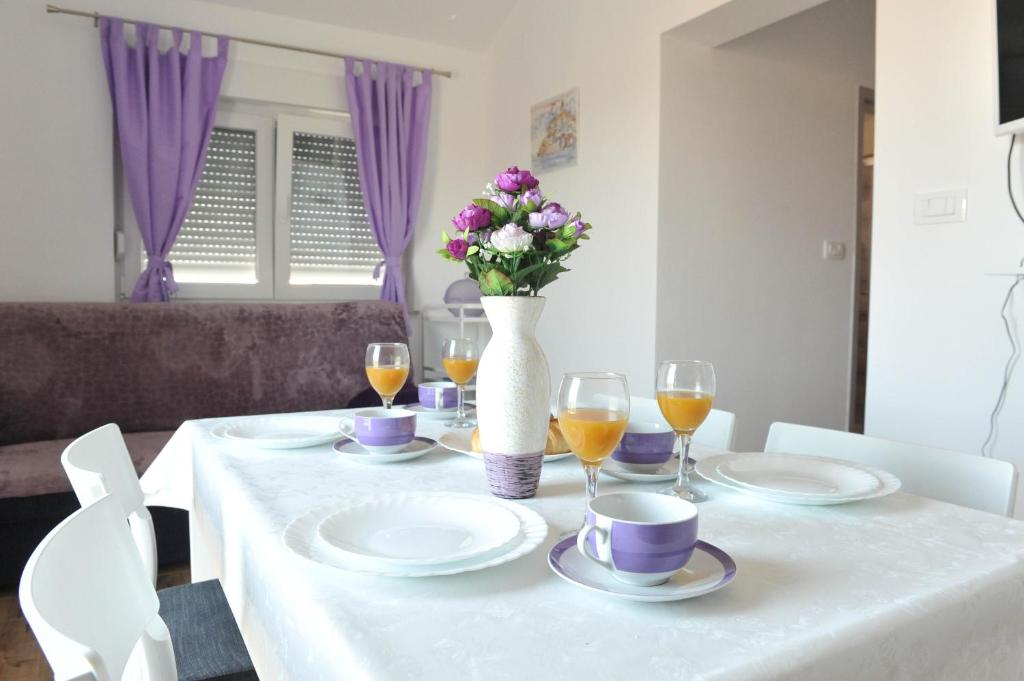 a white table with a vase of flowers and wine glasses at Apartmani Rebecca in Vir