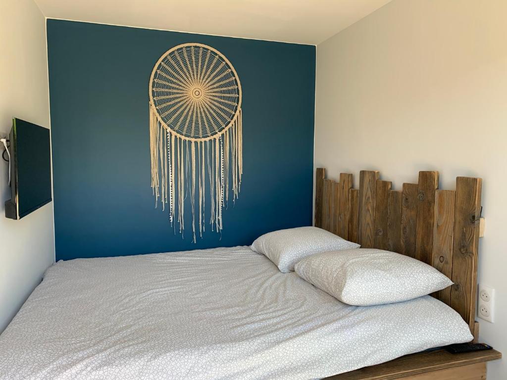 a bed with a blue wall with a dream catcher at Trois Six Vendée in Toulon-sur-Arroux