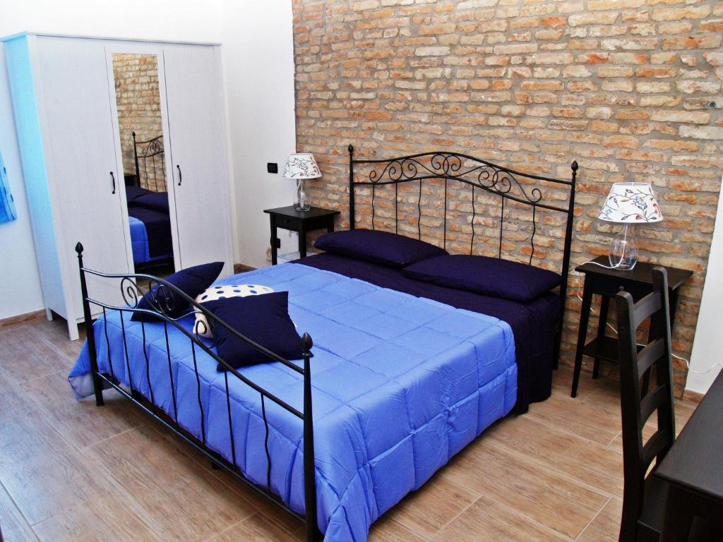 a bedroom with a bed with blue sheets and a brick wall at R&B Locanda Le Bighe in Cona