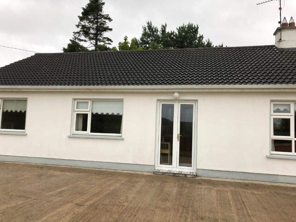 a white house with windows and a driveway at Drumcoura Bungalow in Leitrim