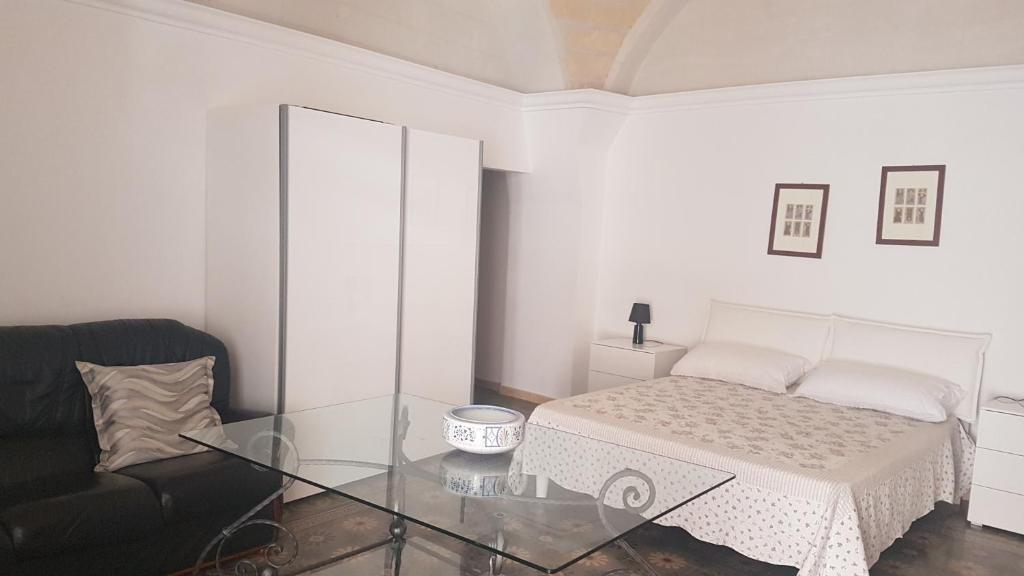 a white bedroom with a bed and a glass table at Jack Room in Trinitapoli