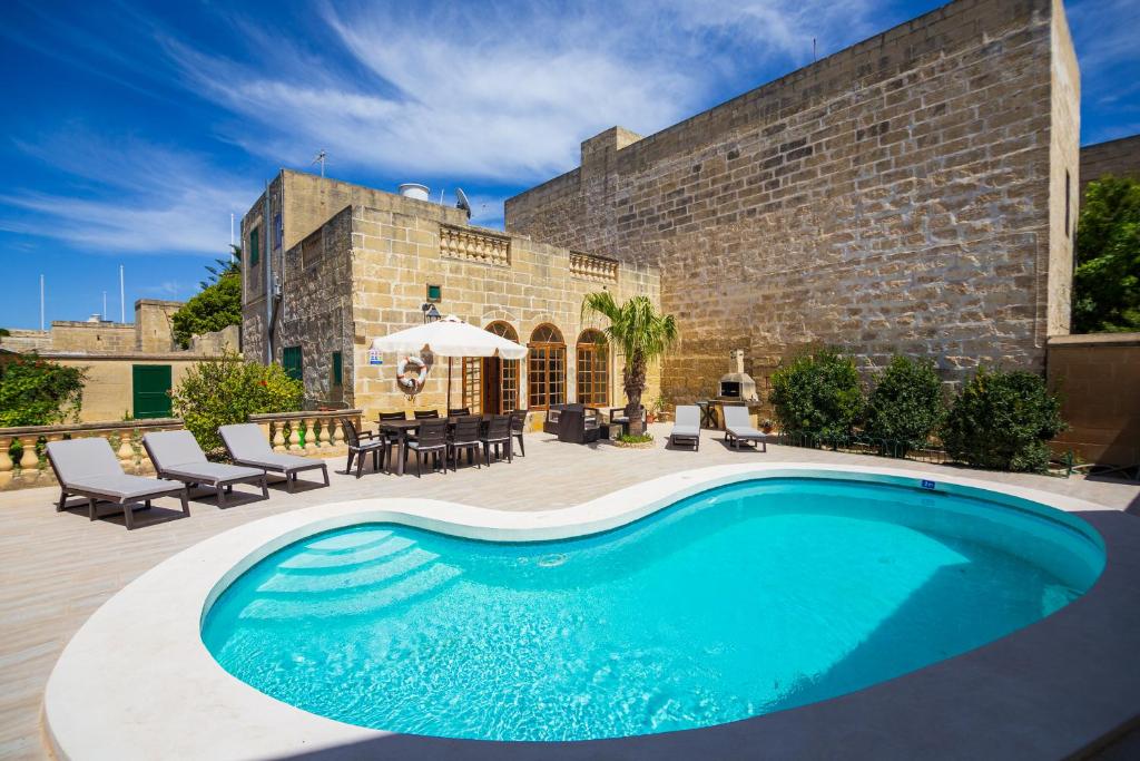 una piscina frente a un edificio de ladrillo en Dar ta' Tumas, en Għarb