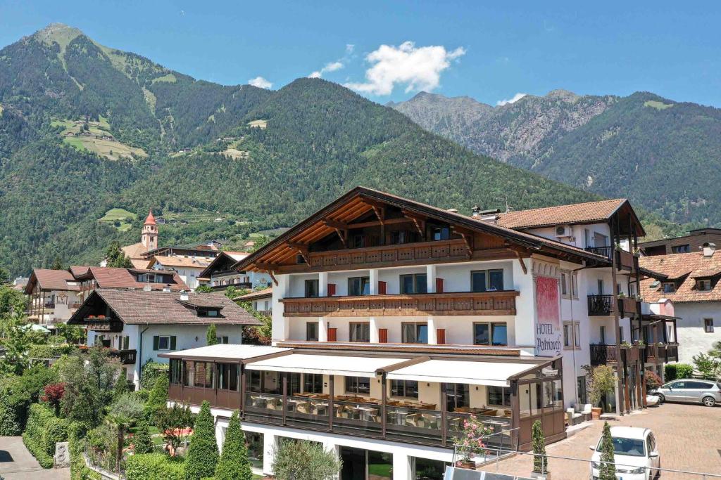 un grand bâtiment dans une ville avec des montagnes en arrière-plan dans l'établissement Hotel Patriarch, à Tirolo