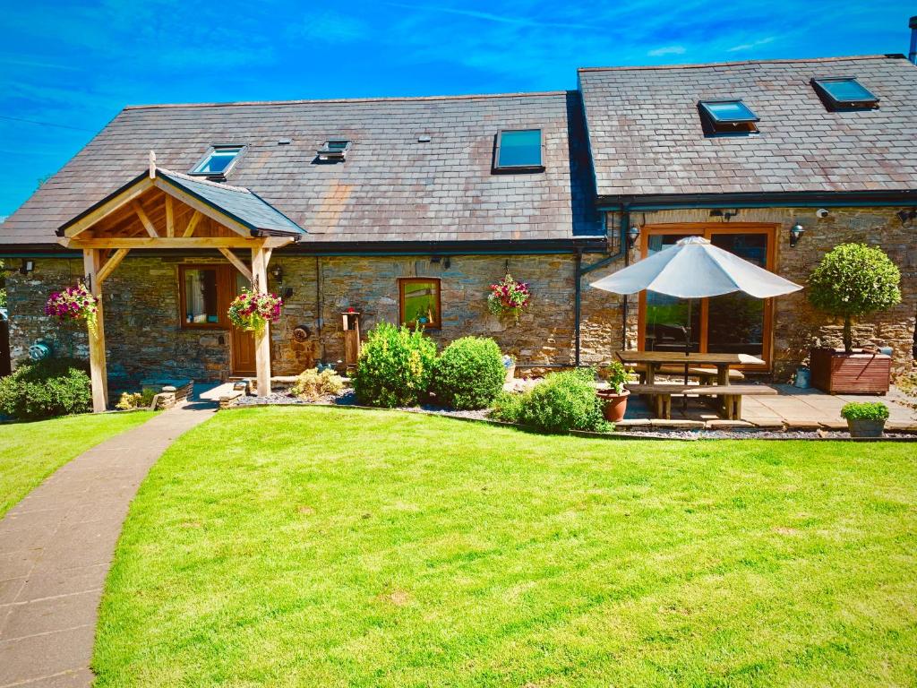 a house with an umbrella and a grass yard at Beudy Bach in Cross Hands