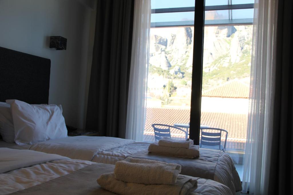 a bedroom with two beds and a large window at Alexiou Hotel in Kalabaka