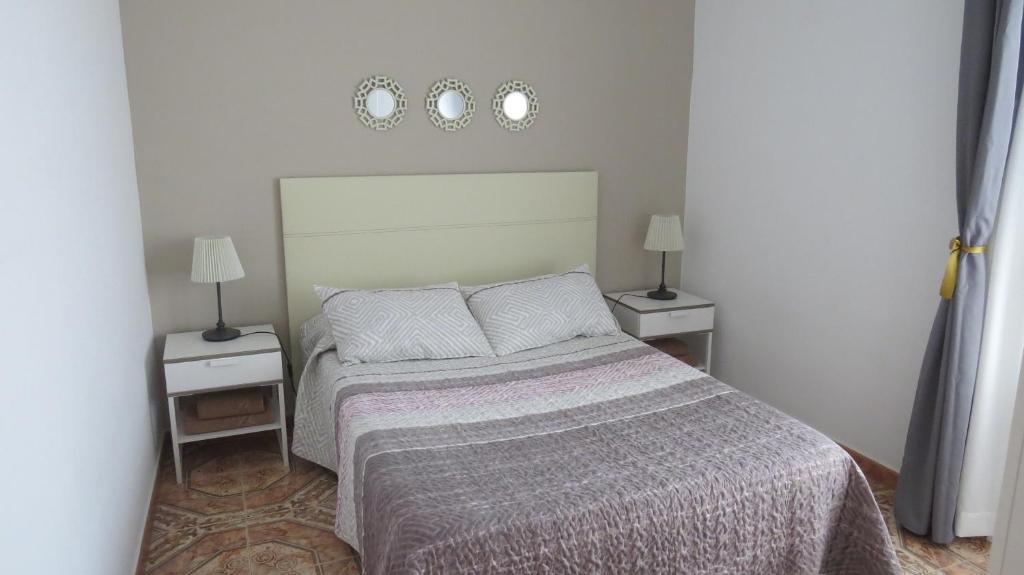 - une chambre avec un grand lit et 2 tables de chevet dans l'établissement Apartamentos Orzola, à Orzola