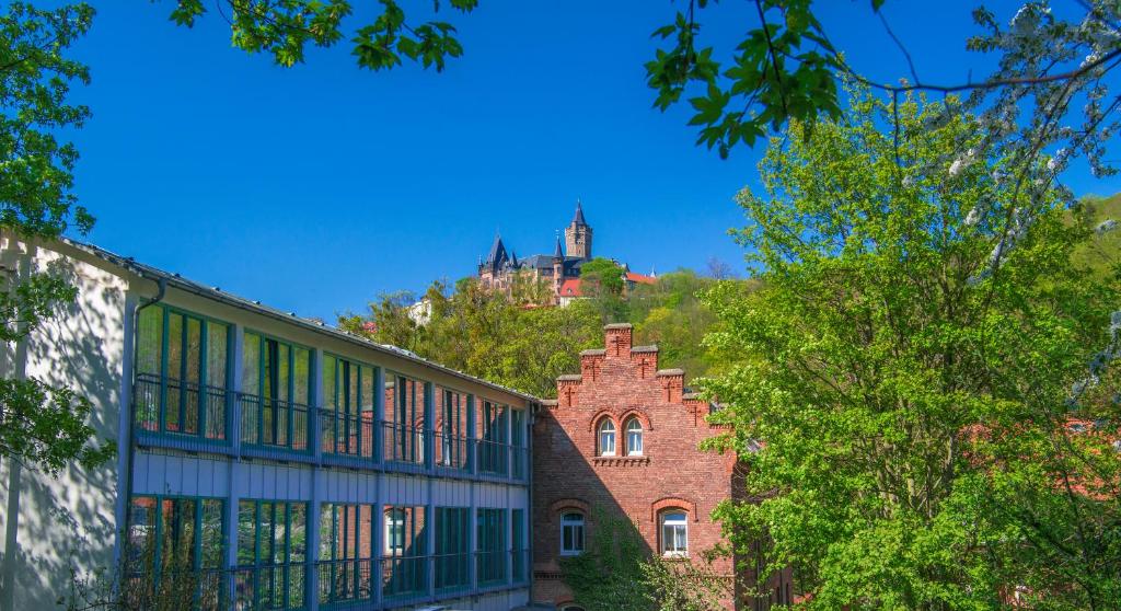 a building with a castle on a hill in the background at CVJM Familienferienstätte Huberhaus in Wernigerode