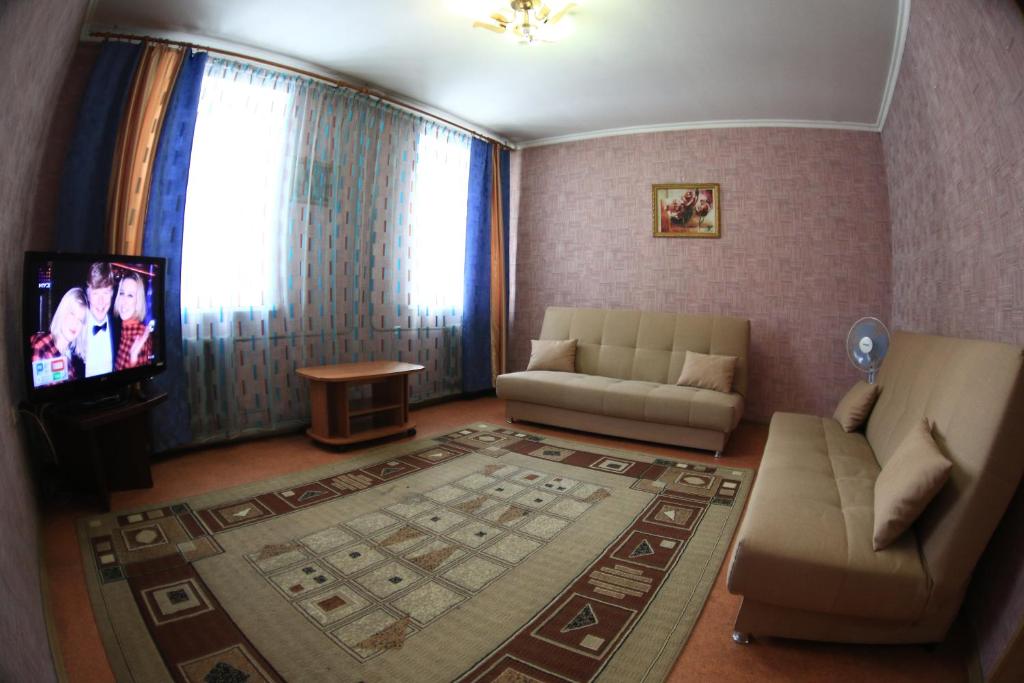a living room with a couch and a tv at Апартаменты у Вокзала in Prokop'yevsk