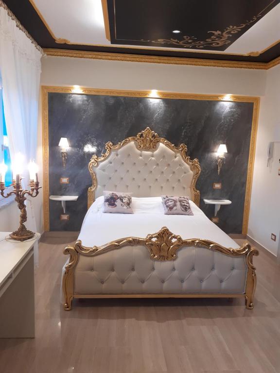 - une chambre dotée d'un grand lit avec un cadre en or dans l'établissement Mare Nostrum luxury suite, à Mazzeo