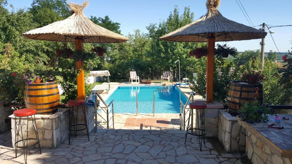 Mala Moštanica的住宿－VILA PEKEČ，一个带两把遮阳伞和椅子的游泳池以及一个游泳池