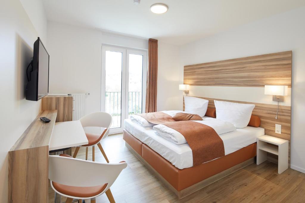 a hotel room with a bed and a desk and a chair at VR-Serviced Apartments Obergeis in Neuenstein