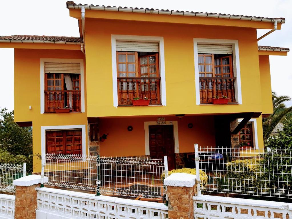 uma casa amarela com janelas e uma cerca em La estrella em Tineo