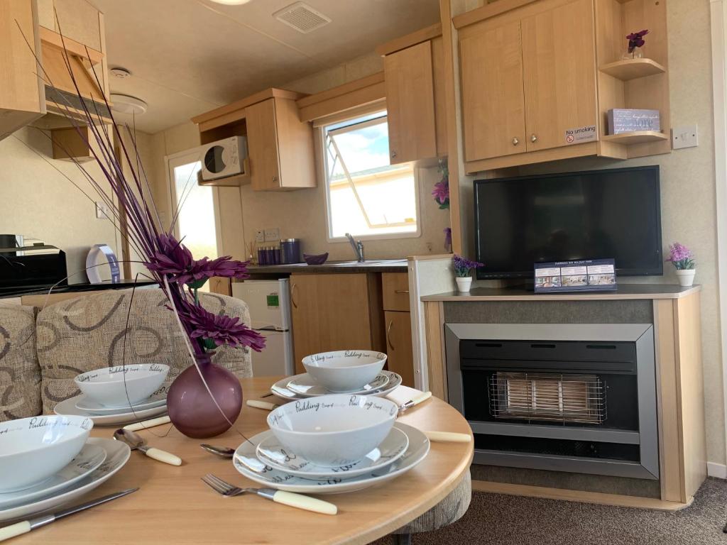a kitchen with a table with bowls and plates on it at Family Holiday Home - Thorness Bay - WIFI in Porchfield