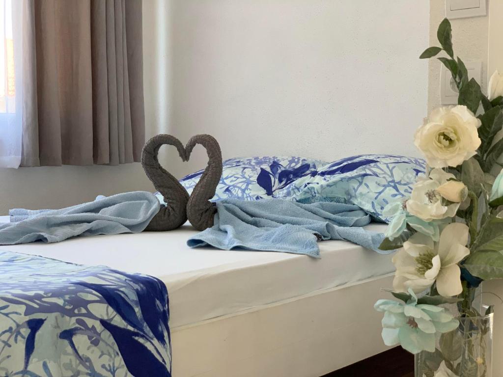 uma cama com lençóis azuis e brancos e dois corações em Apartments Milica em Mirce