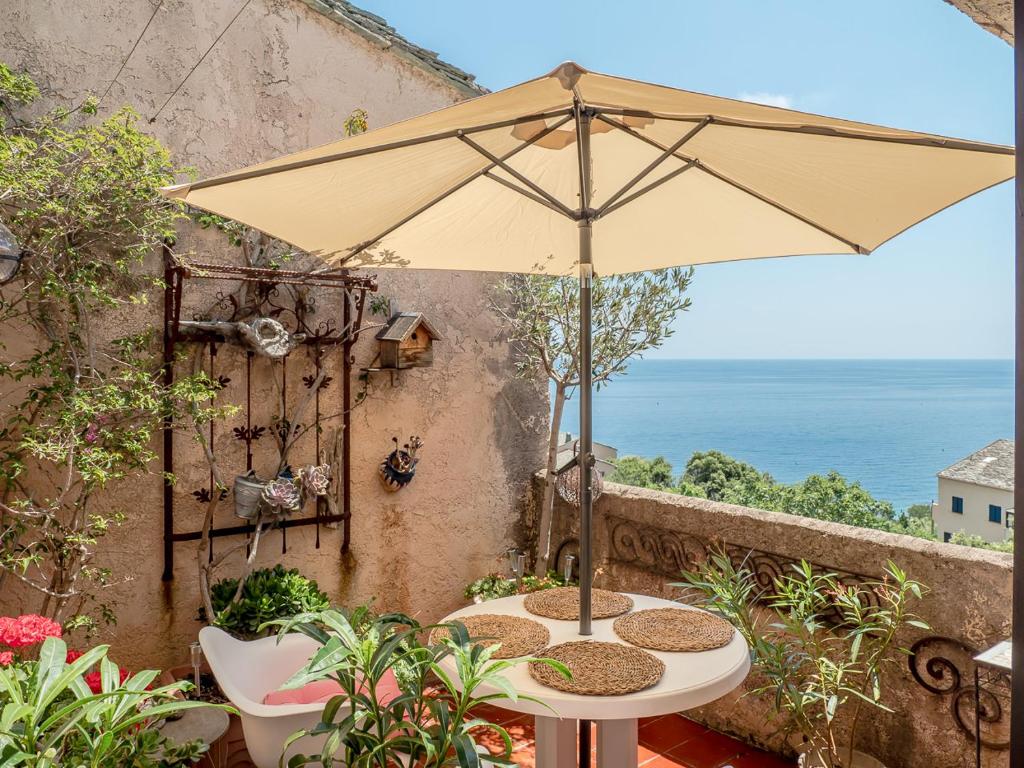 - une table avec un parasol sur le balcon dans l'établissement Residence Les Sources, à Brando