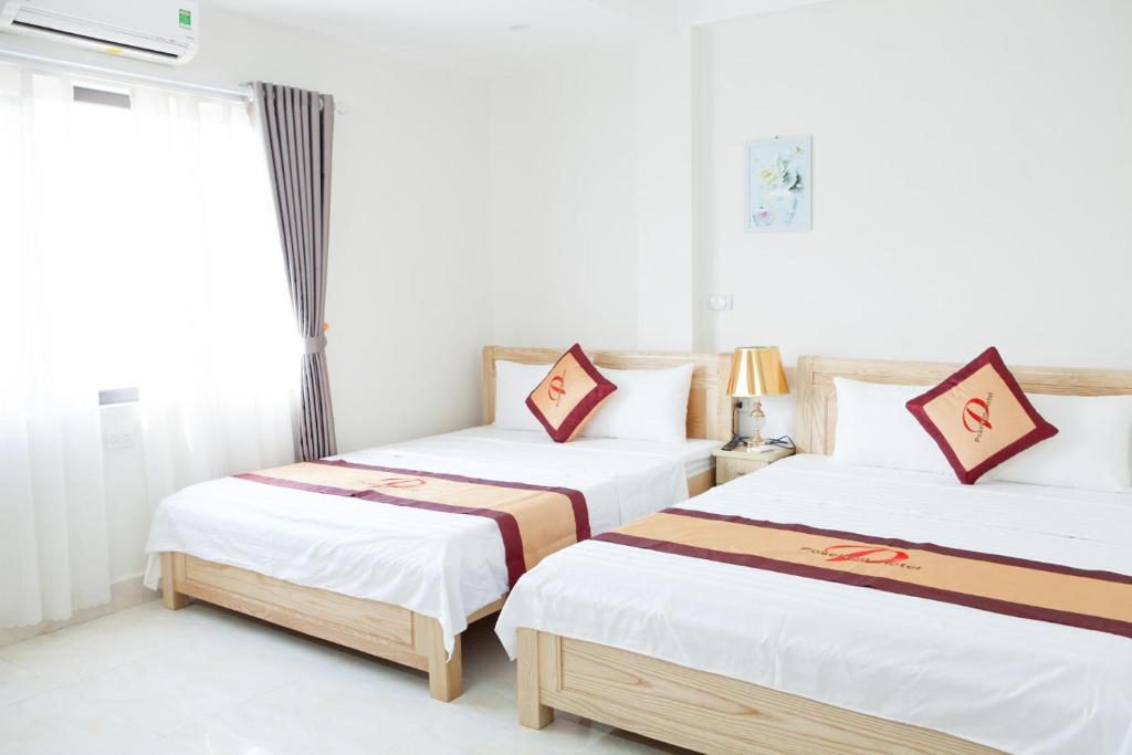 two beds in a room with white walls at Poseidon hotel in Ha Long