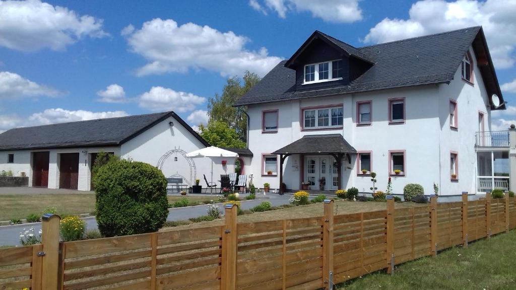 a white house with a wooden fence at Pension Kölzer in Mörsdorf