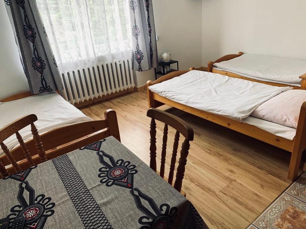 a bedroom with two beds and a table with a rug at Pensjonat Makuch in Korbielów