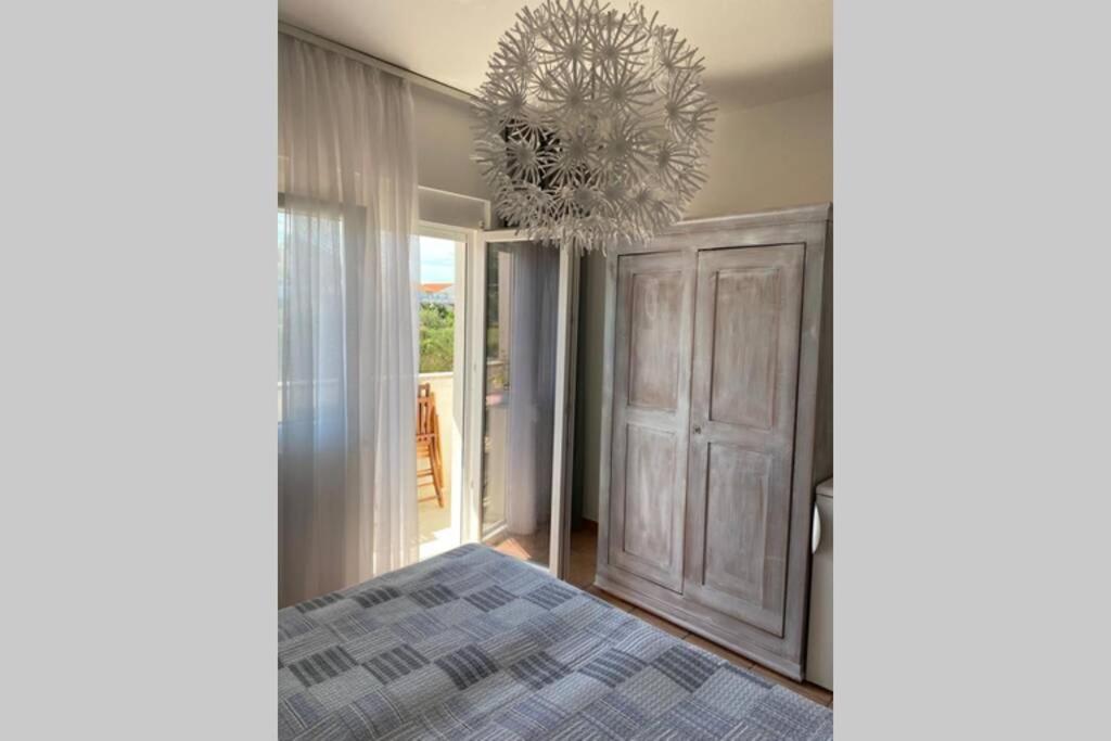a bedroom with a bed and a chandelier at Casa Fumica rooms in Rab