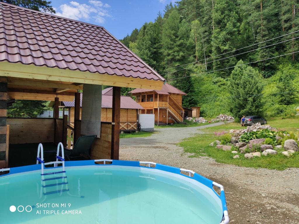 a pool in front of a log cabin with a house at Усадьба в горах in Artybash