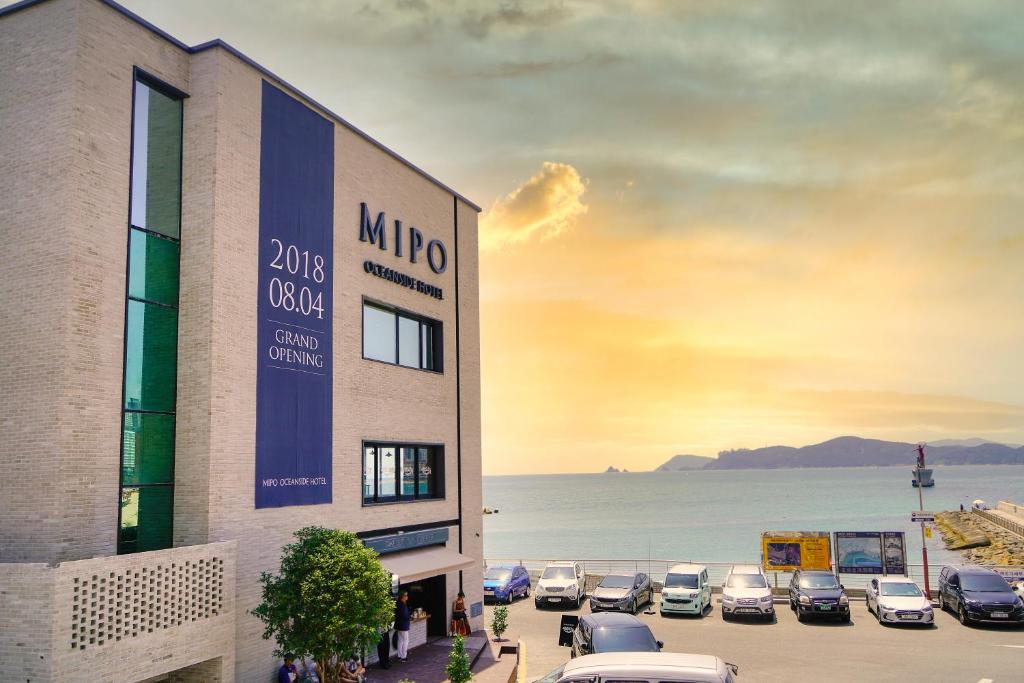 a building with cars parked in a parking lot at Mipo Oceanside Hotel in Busan